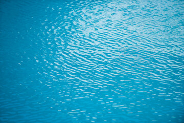 Ripple Water in swimming pool with sun reflection. Wavy water background.