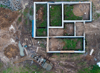 Aerial drone top down view on construction site with reinforced concrete house foundation, brick...