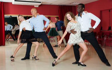 Adult dancing couples enjoying latin dances in modern studio..