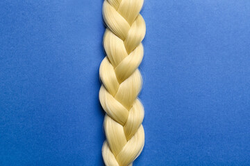 Beautiful braided blonde hair on color background
