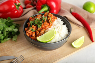 Bowl with tasty chili con carne, rice and vegetables on light background, closeup