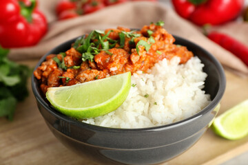 Bowl with tasty chili con carne, rice and lime on table, closeup