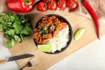 Bowl with tasty chili con carne, rice and vegetables on light background