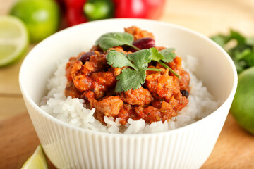 Bowl with tasty chili con carne and rice on table, closeup