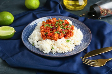 Plate with tasty chili con carne, rice and lime on color background