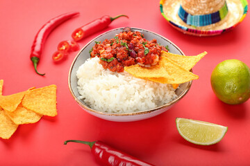 Bowl with tasty chili con carne, rice, nachos, chili pepper and sombrero on color background, closeup