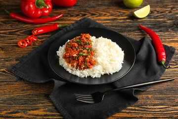 Plate with tasty chili con carne, rice and vegetables on wooden background