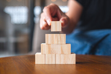 Closeup image of a hand stacking and picking blank wooden cube block