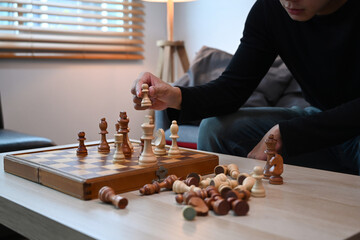 Young man sitting on couch and playing chess.