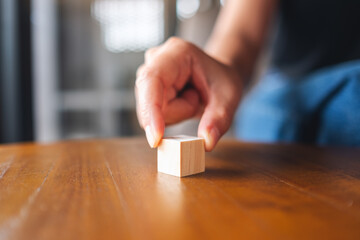 Closeup image of a hand choosing and picking a piece of blank wooden cube block