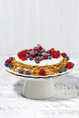 healthy sweet oatmeal cake with yoghurt and fresh berries on a stand, vertical