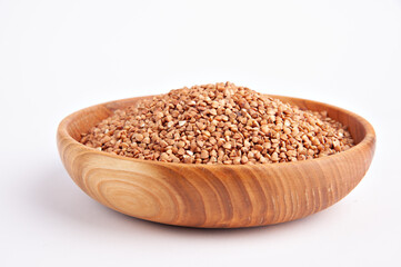 Raw buckwheat groats in a wooden bowl on a white background 