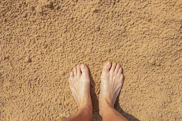 woman barefoot on the sand after the rain. Smooth sexy female legs outdoors walking in the sand....