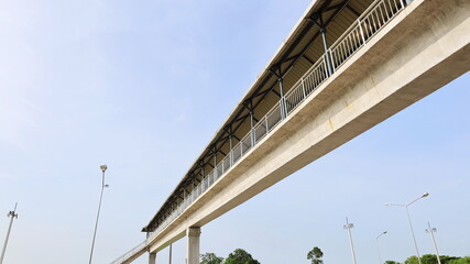 Bridge over the highway with a roof. Cement overpass for pedestrians crossing the road for safety in bottom view on blue sky background with copy space. Selective focus