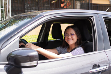 Very smiling young woman driving her new car