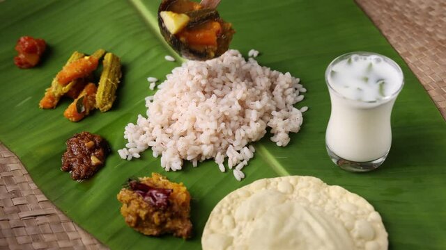 Serving sambar curry Onam sadhya Kerala Matta rice Kerala Red rice Rosematta rice, parboiled cooked rice served banana leaf vegetarian meals Indian rice, Sri Lanka India 4K slow motion video footage