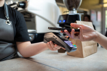Close-up of payment by phone with NFS technology on the phone with a contactless terminal in a cafe shop or cafeteria. Mobile phone or smartphone for order payment with nfs technology.