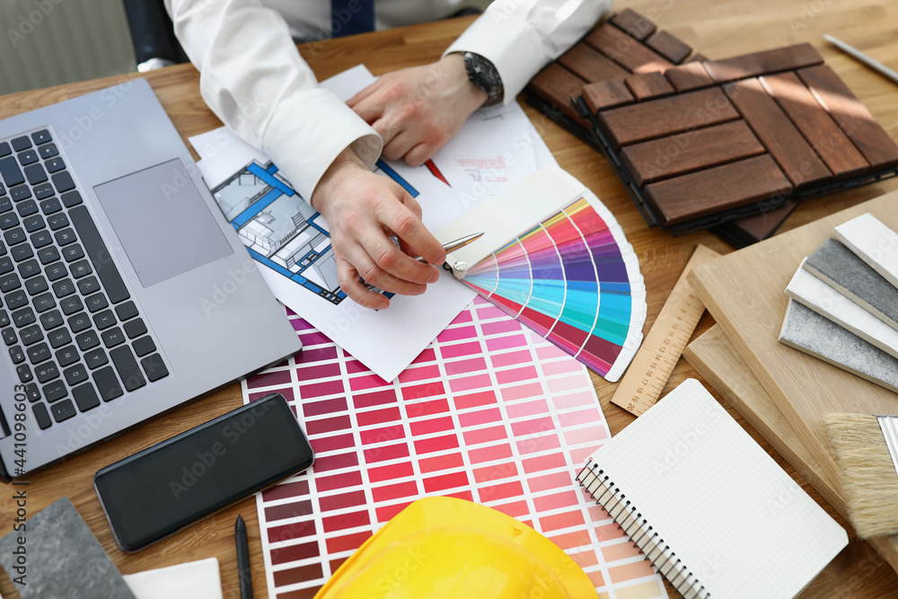 Wall mural male designer architect picks colors from color palette at workplace