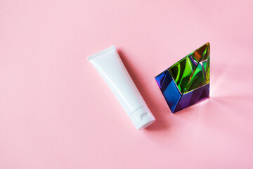 White plastic tube mockup with moisturizer cream, shampoo or facial cleanser and glass pyramid...