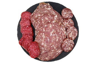 Different tasty sliced salami sausage on a black slate serving board isolated on white background
