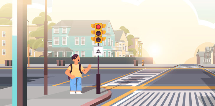 schoolboy with backpack waiting for green traffic light to cross road on crosswalk road safety concept
