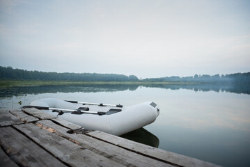 Inflatable boat on the lake water background near the old wooden pier.