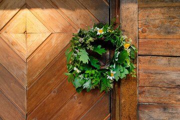 Green and flower wreath on vintage wooden bath house doors - obrazy, fototapety, plakaty