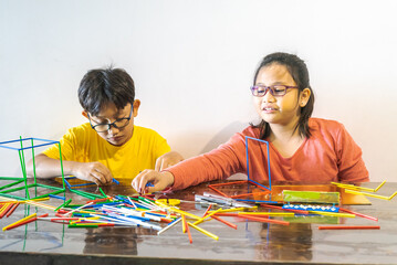 Young children are constructing colorful plastic sticks with glue gun. fun with building geometric...