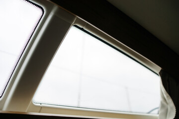 Obraz premium Boat trip on the river. Details about the sailing yacht. In the summer we go by boat. A white yacht with full sails. Leisure, sports, recreation theme. Window from inside the cabin 