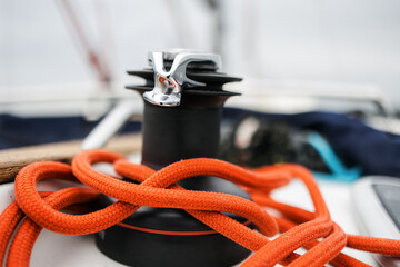 Boat trip on the river. Details about the sailing yacht. In the summer, we go by boat. A white yacht with full sails. Leisure, sports, recreation theme. Close-up view of a reel with a rope. Attachment
