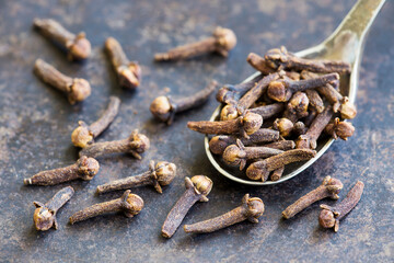 Organic, aromatic spices, cloves on a spoon. Thanksgiving or christmas cooking background.