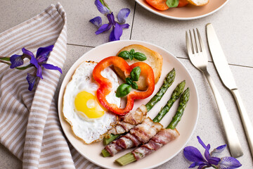 Toasted egg with asparagus, bacon and bell pepper on a plate. Delicious and healthy breakfast.