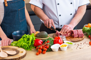 Young woman and man prepare food and host a cooking show. The bloggers stream from modern kitchen. Healthy food preparation.