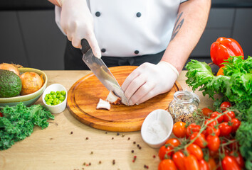 Young chef is cutting octopus in a modern kitchen. The man prepares food at home. Cooking healthy and tasty food.