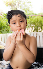 Hungry asian boy eating a sandwich in the water tub.Unhealthy food Concept..
