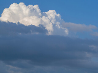 A large fluffy beautiful cumulonimbus cloud high on a sunny day. Beautiful huge soft clouds form in the blue sky