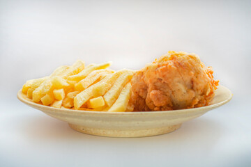Plate with fried chicken leg and fries on a light background.