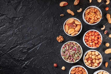 Nuts on a black background with a place for text, overhead flat lay shot of peanuts, walnuts etc