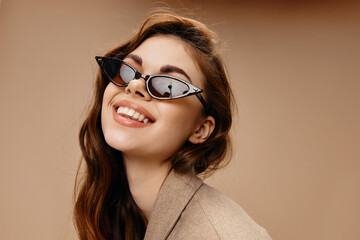 portrait of happy woman in sunglasses smile beige background cropped view