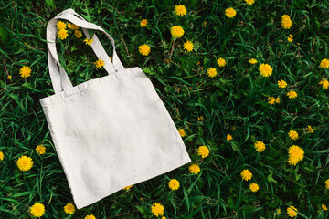 White cotton or mesh bag on dandelion grass background. Zero waste, no plastic, eco friendly...