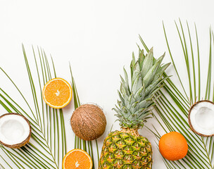 summer background with fresh oranges, coconuts and pineapples on a light gray background