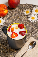 Close-up of yogurt with strawberry, peach and chia in a black ceramic cup. Healthy and tasty breakfast.