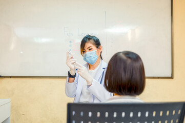 Coronavirus vaccination. Covid-19 vaccine. Doctor giving vaccinations to schoolchildren at School...