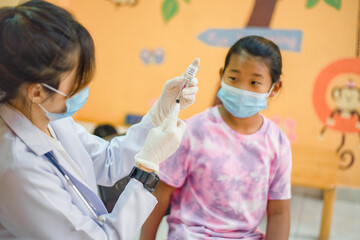 Coronavirus vaccination. Covid-19 vaccine. Doctor giving vaccinations to schoolchildren at School...
