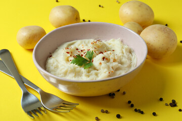 Plate of mashed potatoes and ingredients on yellow background
