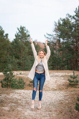 Obraz premium Young beautiful blonde long haired woman with raised hands over green natural forest background outdoor.