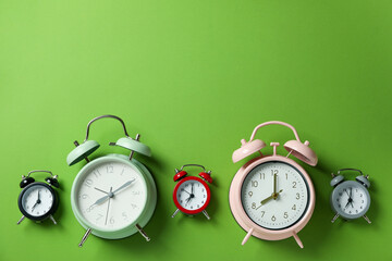 Different multicolor alarm clocks on green background