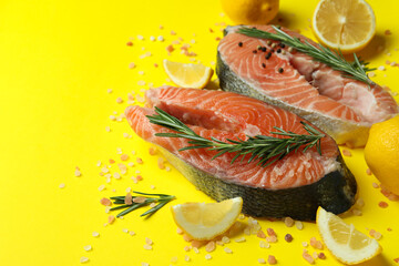 Fresh raw salmon and spices on yellow background