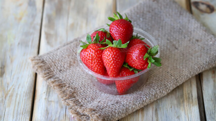 Fresh ripe strawberries in a plastic bowl. Large strawberries.