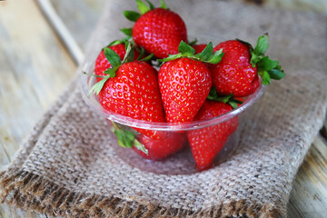 Fresh ripe strawberries in a plastic bowl. Large strawberries.